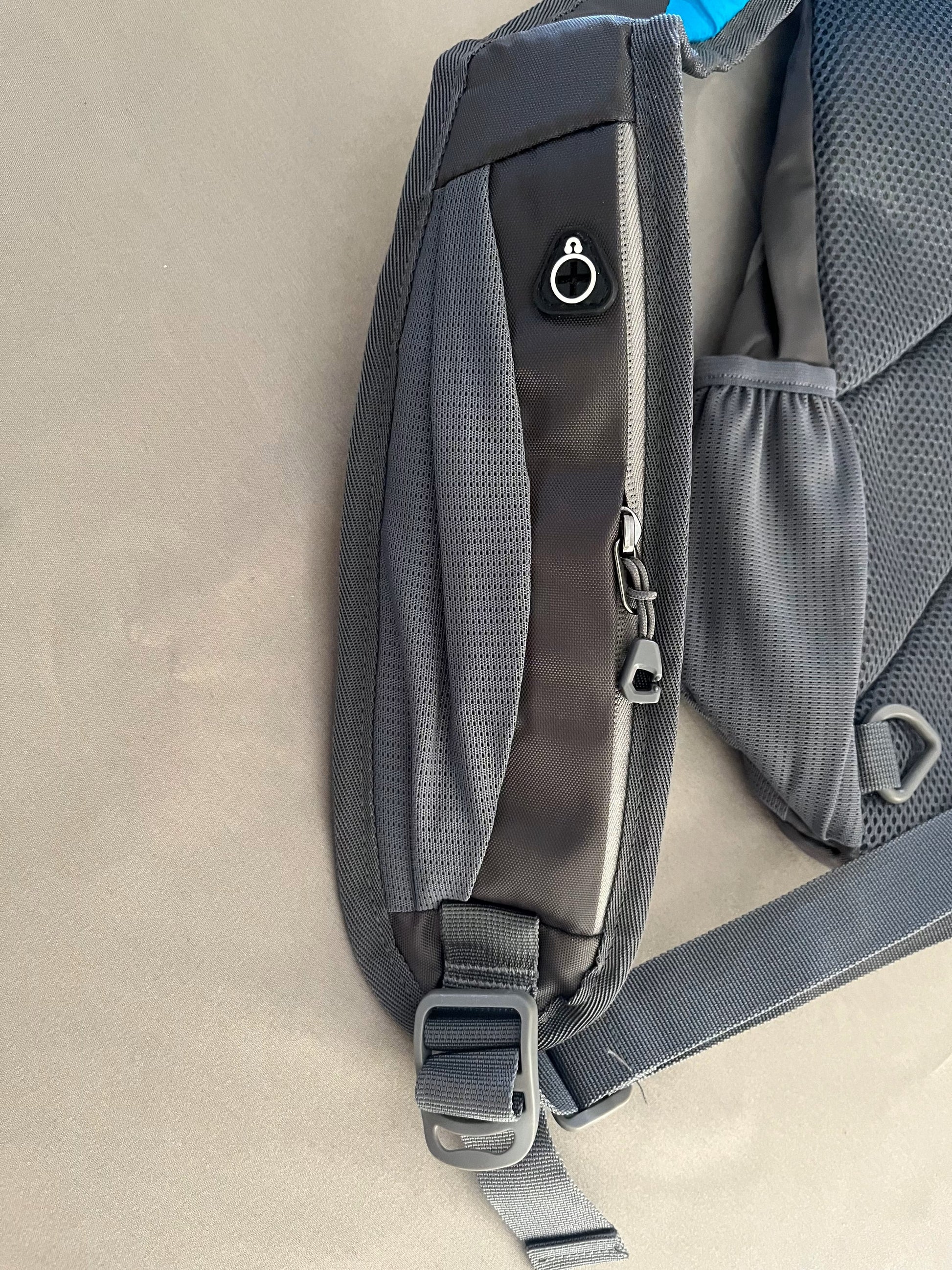 Gray backpack with a focus on the shoulder strap and back panel on a beige background