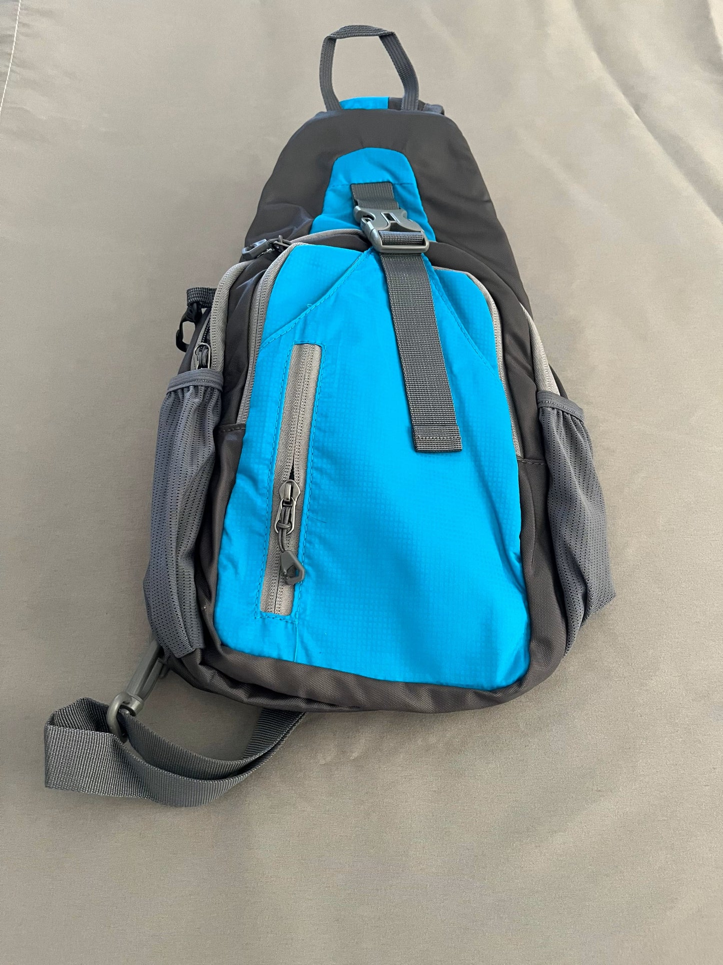 Blue and gray sling bag on a beige surface